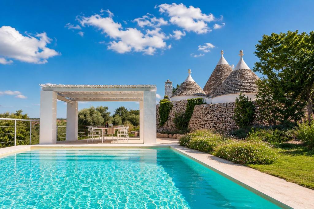 a pool with a pergola next to a house at Trulli Santa Maria dei Grani - Authentic Puglia Trulli with Private Pool & Scenic Garden in Ceglie Messapica