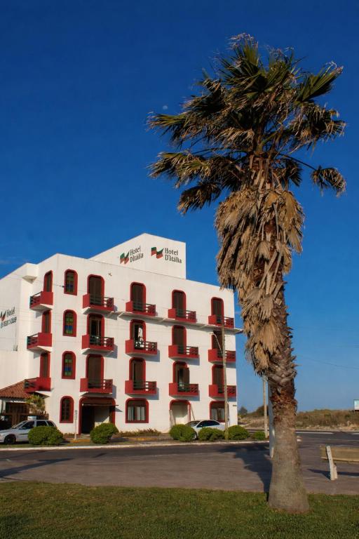 a palm tree in front of a hotel at Hotel D'Italia in Arroio do Sal