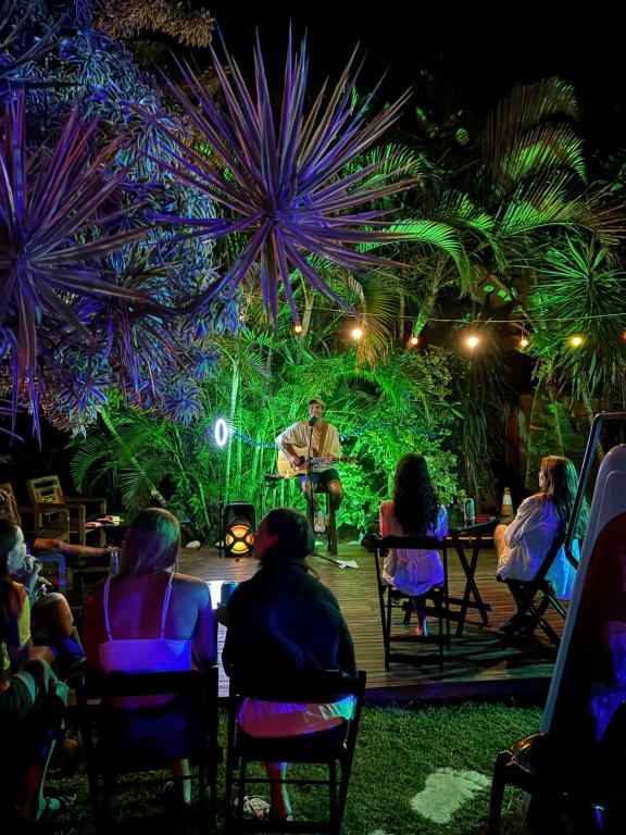 a group of people sitting in chairs watching a man on a stage at Numa Boa HOSTEL Búzios in Búzios