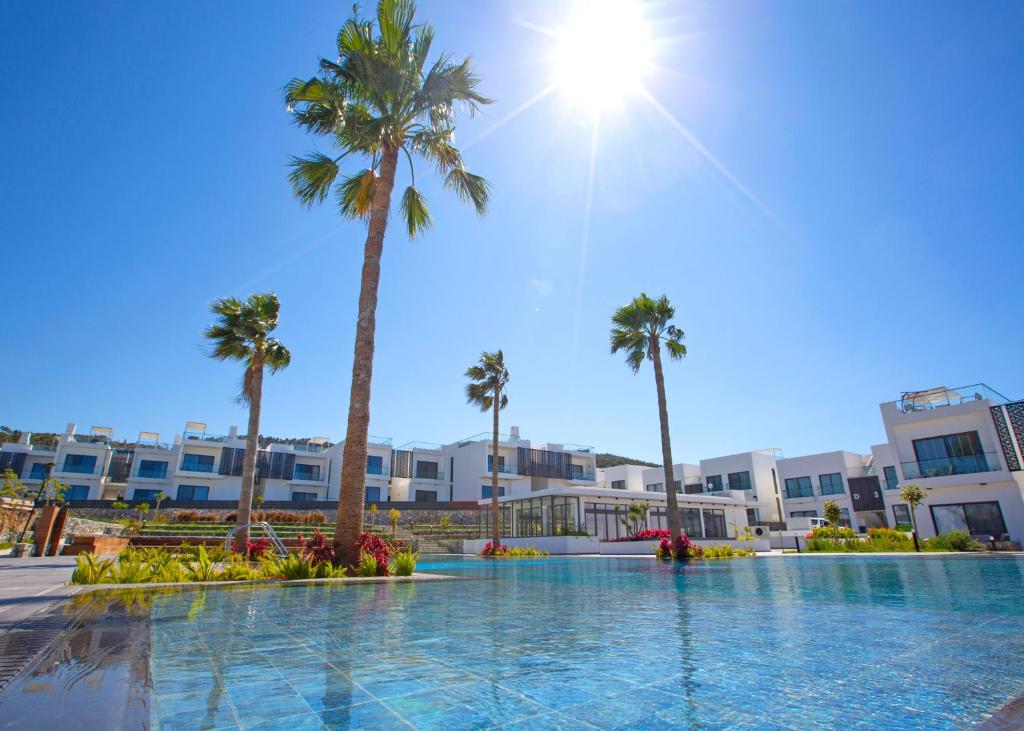 a swimming pool with palm trees and buildings at Aqualina B3-2 by HolidayKeys in Kyrenia