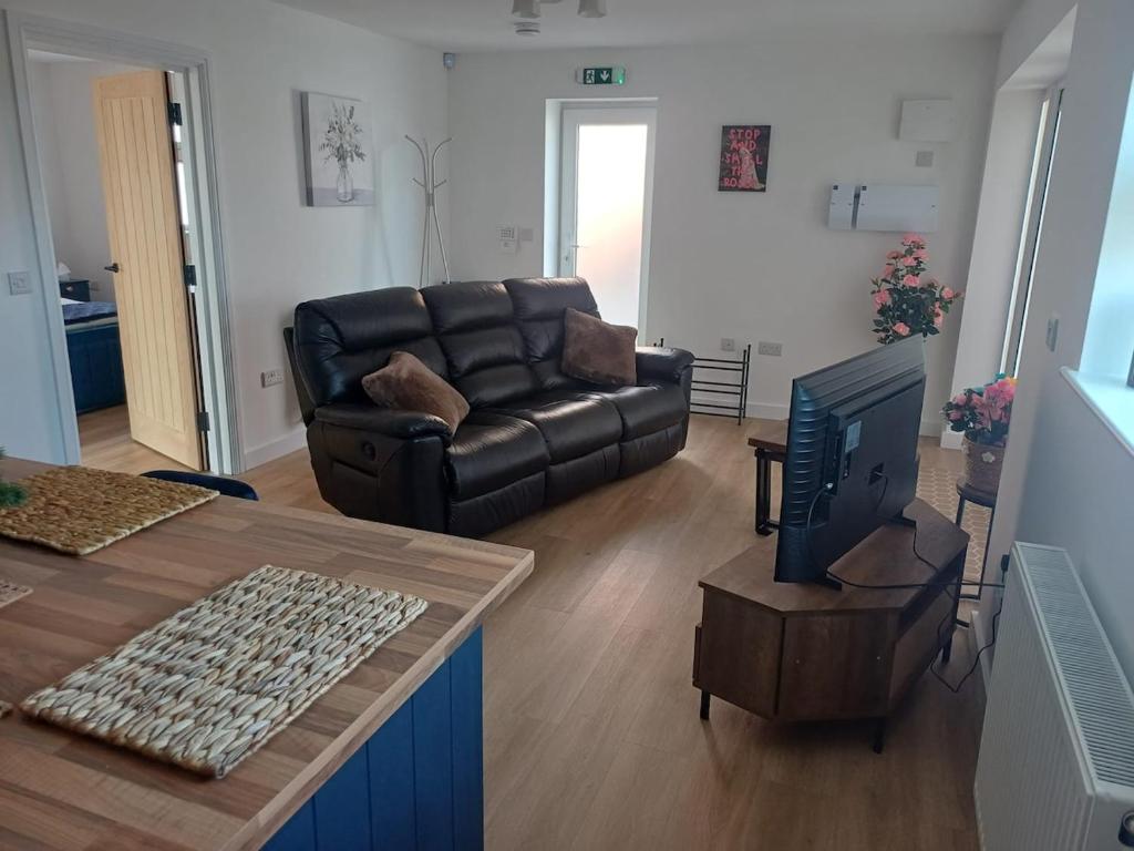 a living room with a leather couch and a television at Ives End in Buxton