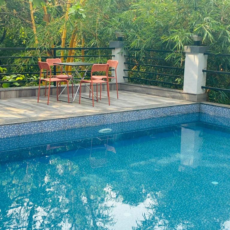 a table and chairs next to a swimming pool at Amazinn Hotel in Lonavala