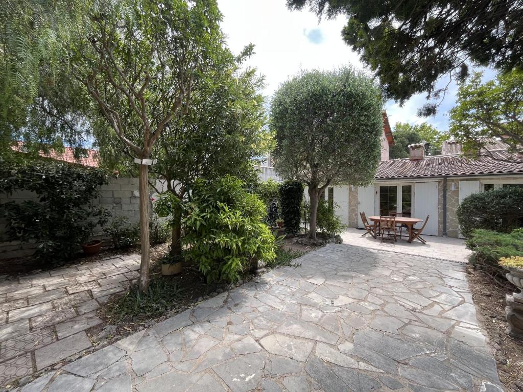 a patio with a table and trees in front of a house at Fréjus Plage - 5mins à pied des plages - Maisonette avec jardin, 4p, au calme absolu in Fréjus