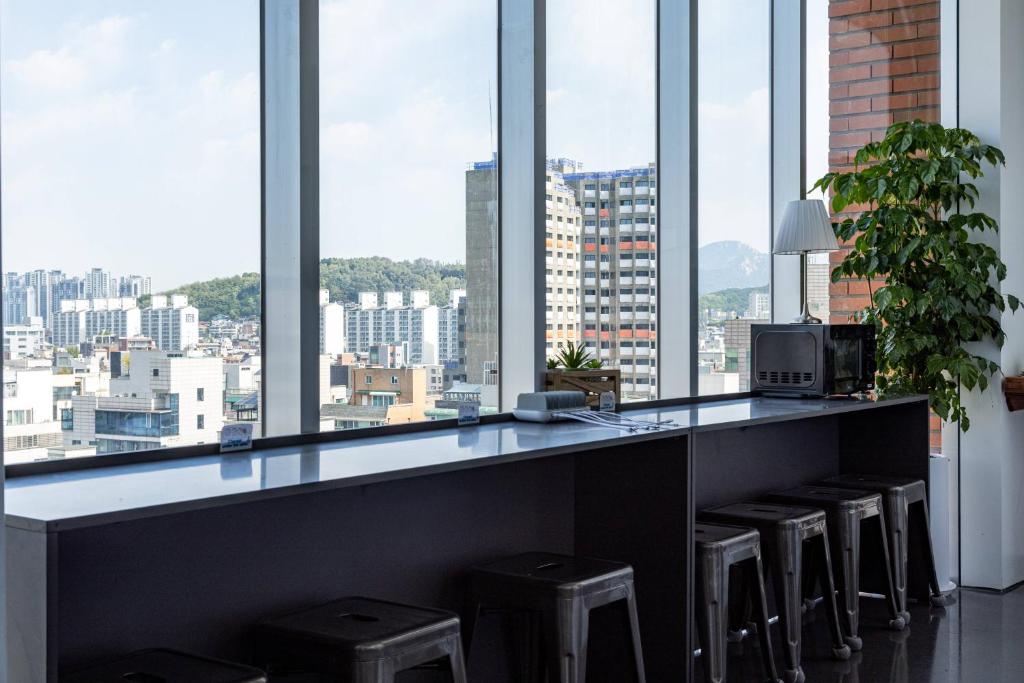 Eine Bar mit Hockern in einem Raum mit großen Fenstern in der Unterkunft Lazy Cube in Seoul