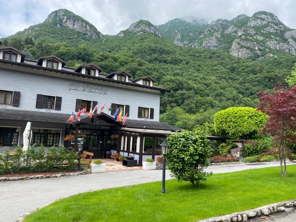a building with flags in front of a mountain at Hotel Al Verde in Mandello del Lario