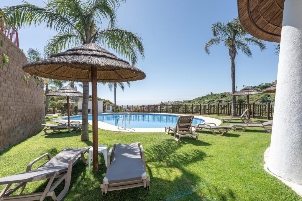 a swimming pool with chairs and an umbrella and a pool at Alcaidesa Golf in La Alcaidesa