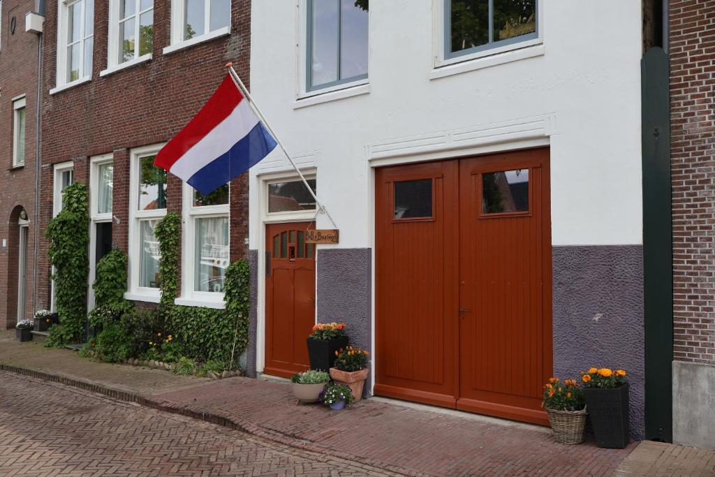 a flag flying in front of a building with red doors at B&B de Beurtvaart in Dokkum