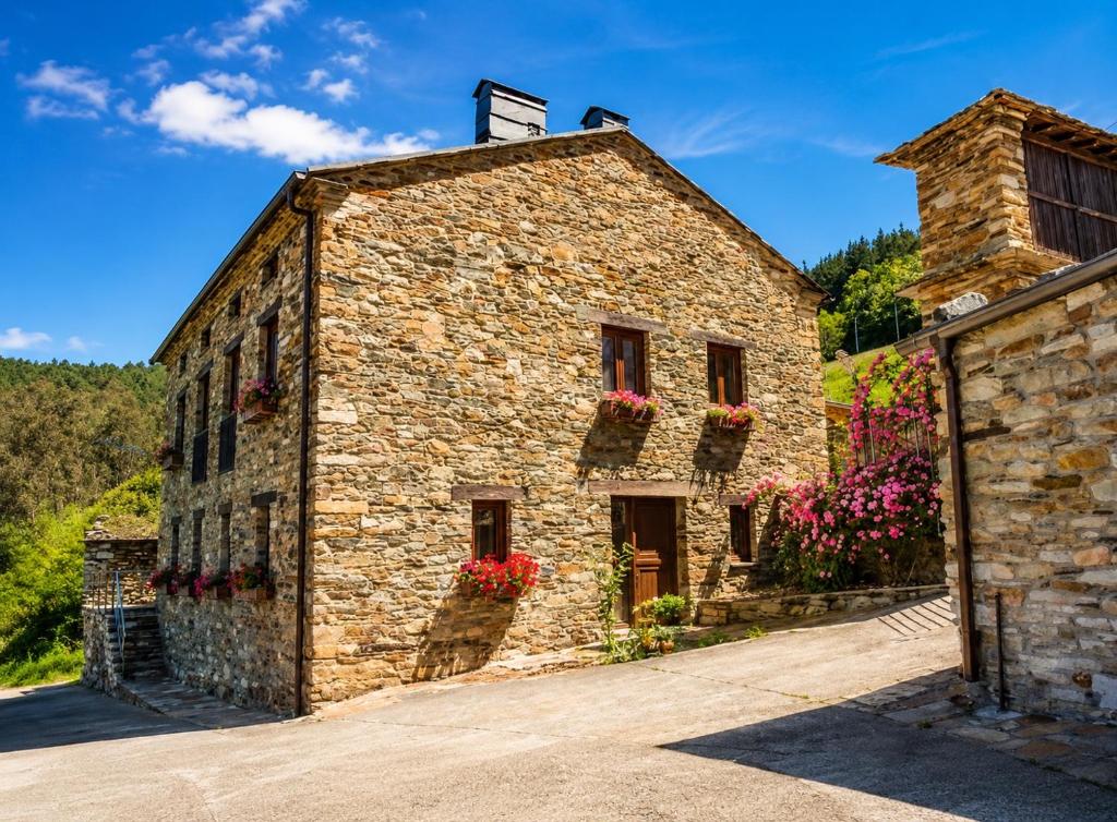 a stone building with flower boxes on the windows at RURAL PRADO in San Tirso de Abres