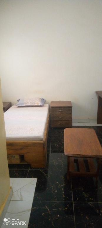 a bedroom with two beds and two wooden tables at Chambre d'hôtes à louer in Pikine