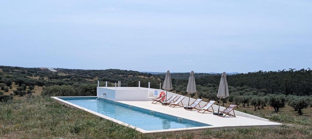 a swimming pool with lounge chairs and umbrellas at Herdade dos Calvinos, Monte 2 - Alandroal in Parreiras