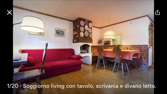a living room with a red couch and a table at Appartamento Borealis in Cogne