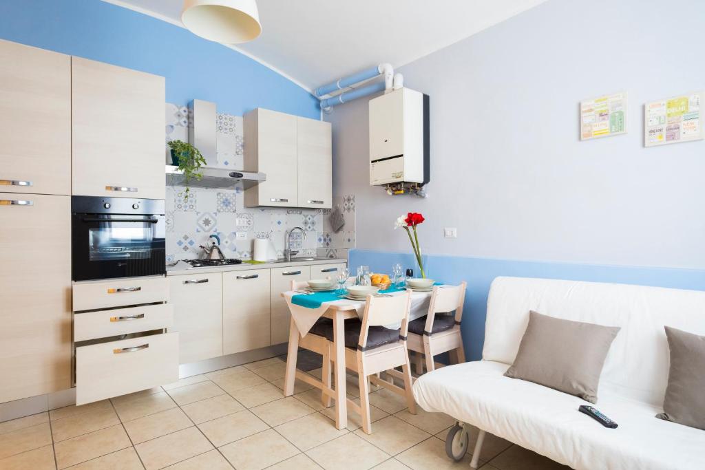 a kitchen with white cabinets and a table and a couch at Polvara Trentuno Accommodations in Lecco