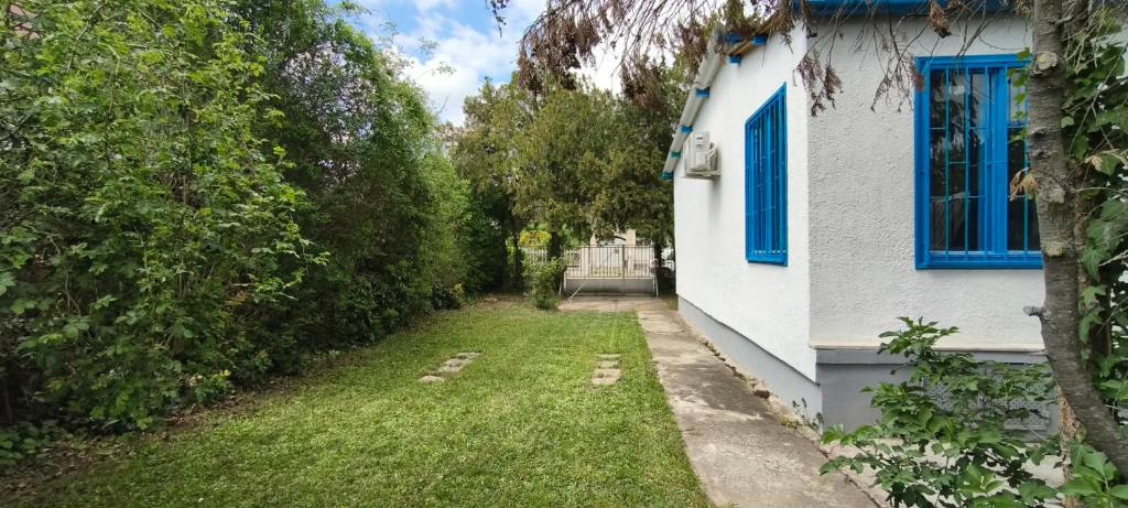 a yard next to a white house with blue windows at A Görög kis Ház in Velence