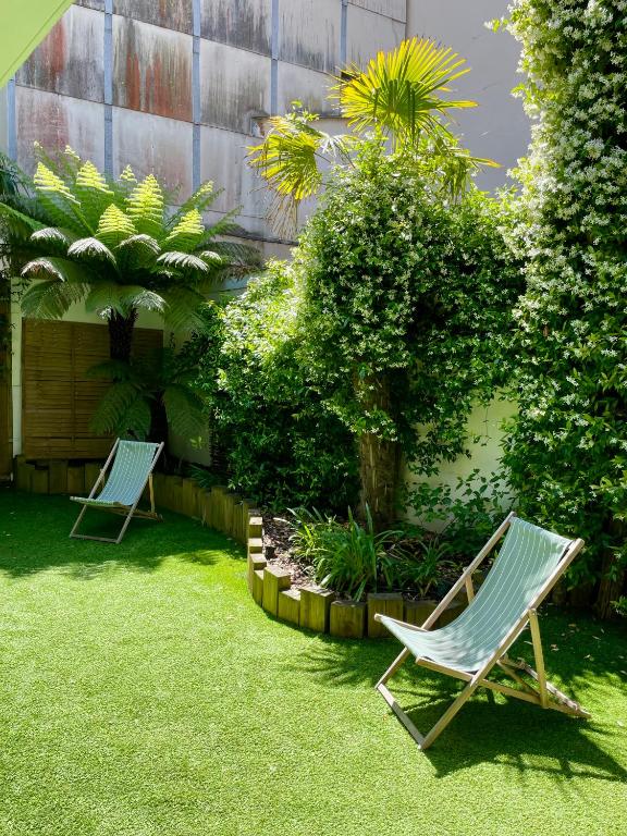 two lawn chairs sitting in a yard with plants at Suite indépendante avec jardin, 2 chambres communicantes, hyper centre Arcachon in Arcachon