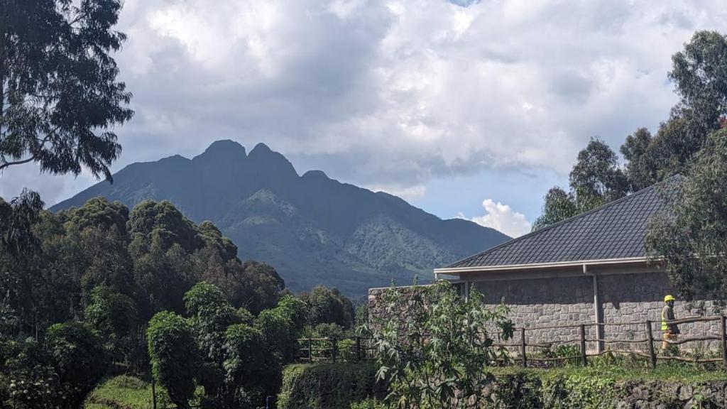a house with a mountain in the background at Ubucuti Gorilla Lodge in Kinigi
