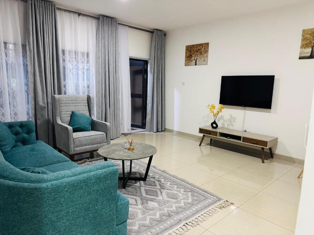 a living room with two chairs and a flat screen tv at Vantage Suite in Lilongwe