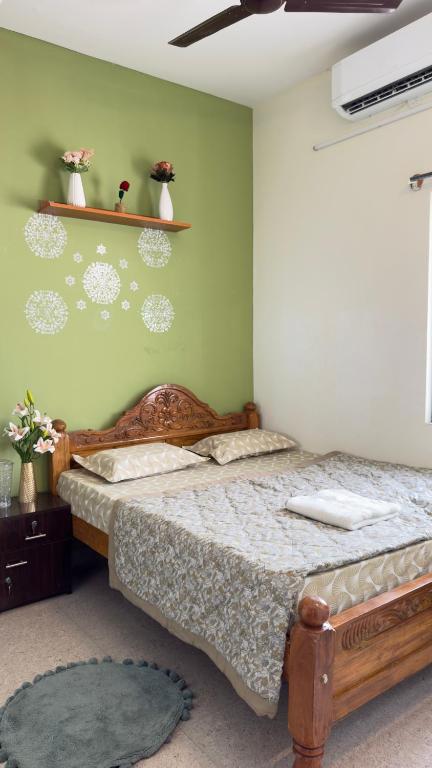 a bedroom with two beds and a green wall at Trayi stay in Mysore