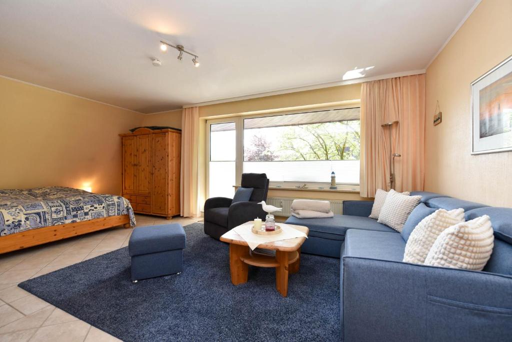 a living room with a blue couch and a bed at Haus "Luv und Lee" Appartement LUV34 in Döse