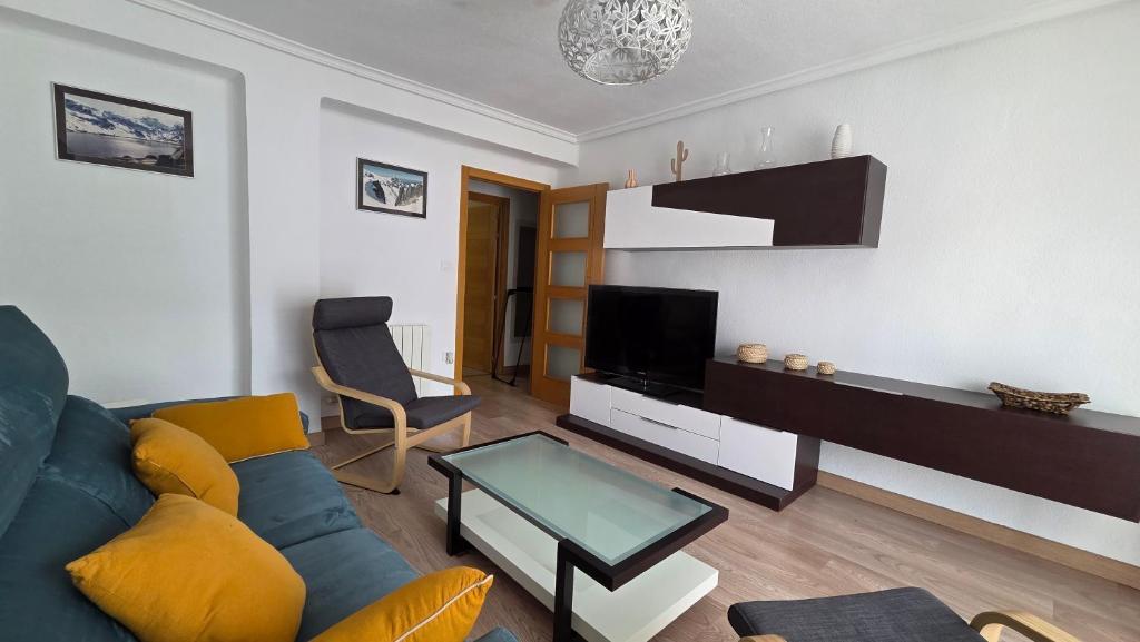 a living room with a blue couch and a tv at Vivienda Mirasierra in Béjar