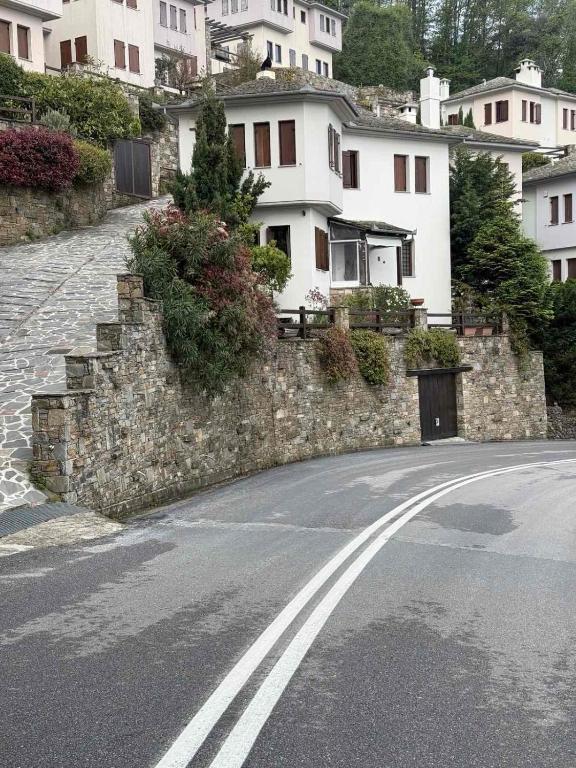 an empty road with a stone wall and houses at M Villa Pelion in Tsagarada