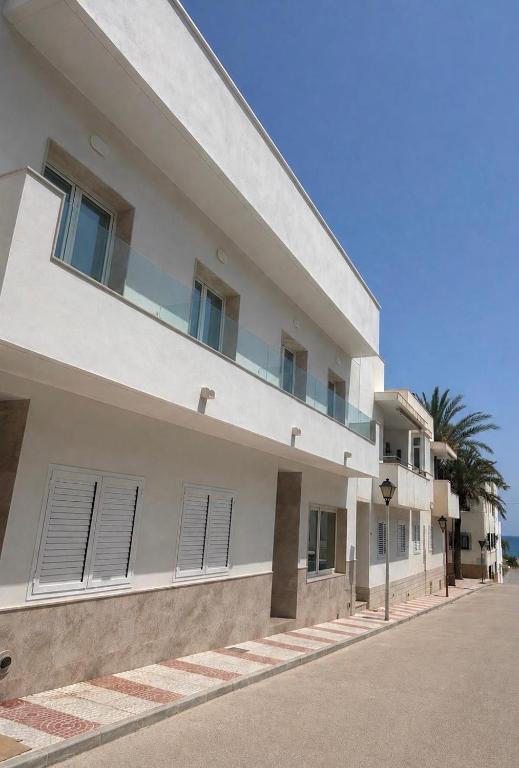 a white building with windows and a palm tree at La LLar in Carboneras