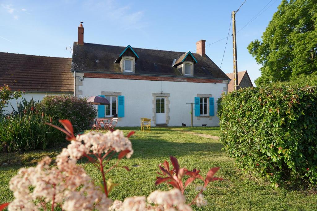 a white house with blue windows and a yard at Domaine la Héroïca in Maisonnais