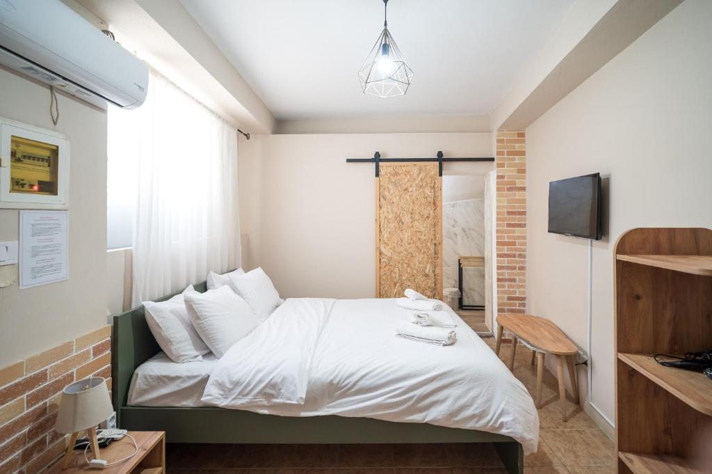 a bedroom with a white bed and a television at Nisaki City Vibes in Chios