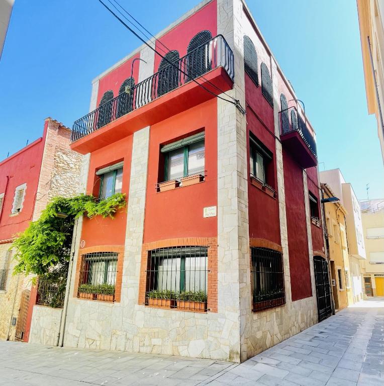 a red building with a balcony on a street at NEW - Casa Palamós - Charming historical home with patio, in the heart of the old town, 100m from beach in Palamós