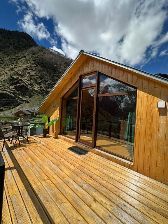 a house with a wooden deck with a table at Cabin AISI in (( Gergeti ))