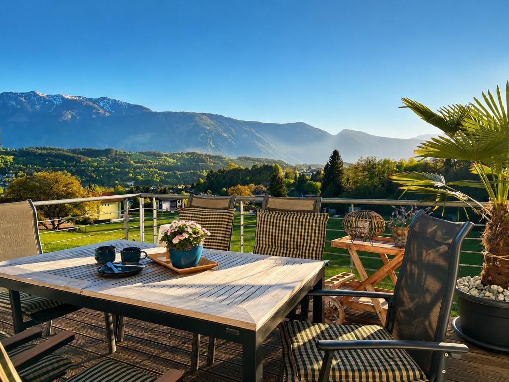 a wooden table on a patio with mountains in the background at EulenHorst - Ferienhaus in Seeboden am Millstätter See mit Sonnenterasse & Bergblick in Seeboden