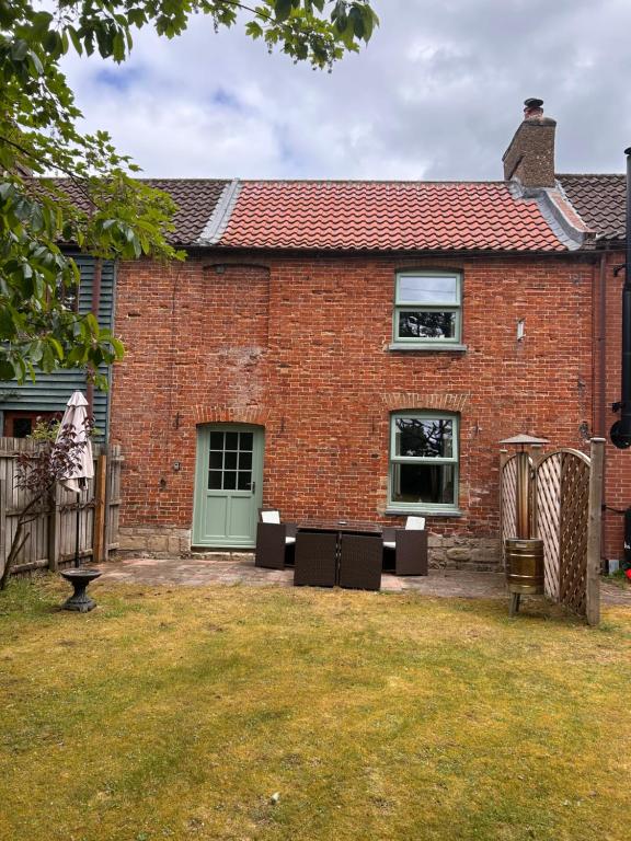 a brick house with a green door and a yard at Herberts Cottage in Wormegay
