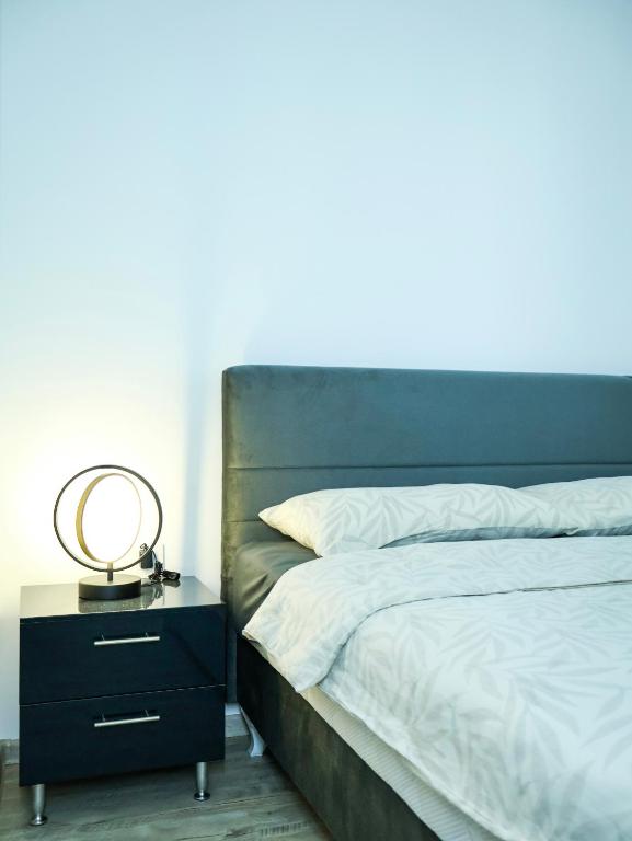 a bed with a nightstand with a mirror on it at Nada Apartman in Prijedor