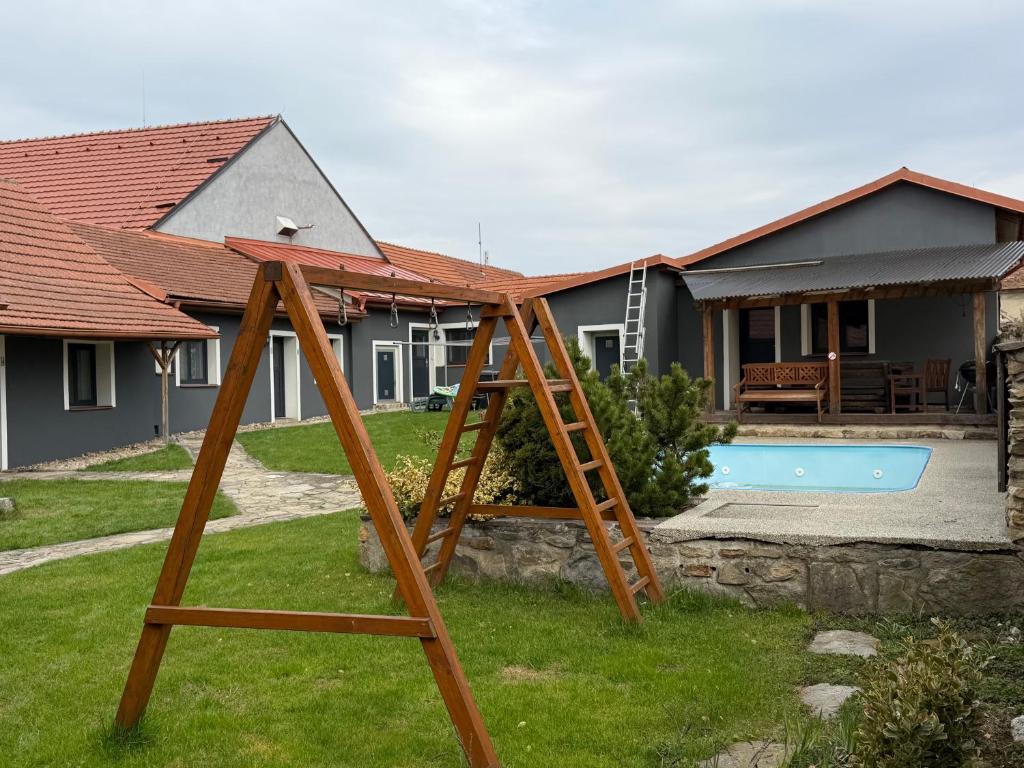 a wooden swing set in front of a house at Penzion u Valešů in Mohelno