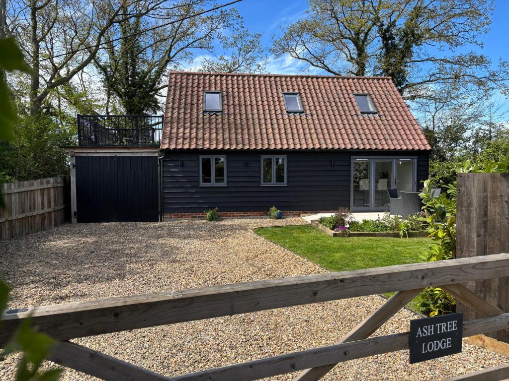 a small black house with a wooden fence at Ash Tree Lodge in Norwich