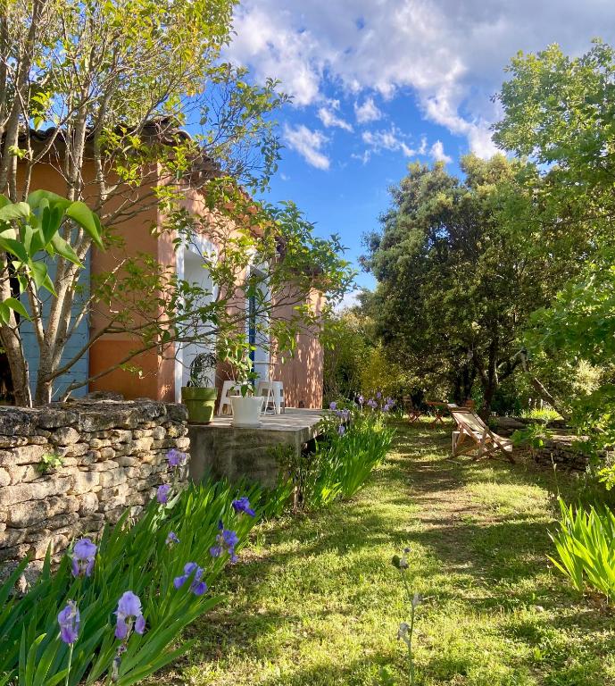 a garden with purple flowers and a stone wall at Les Iris in Bonnieux