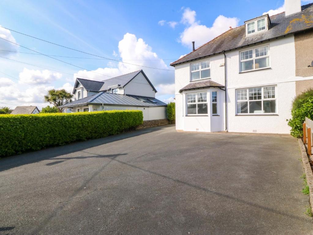 a white house with a driveway in front of it at Bryniau in Pwllheli