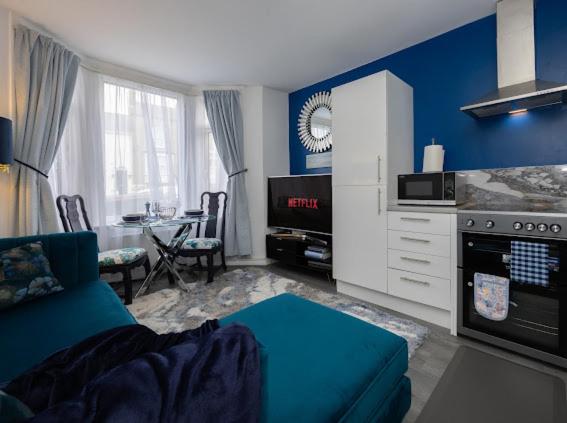 a living room with a couch and a kitchen with a table at Reverie Escape by Halisi in Ramsgate