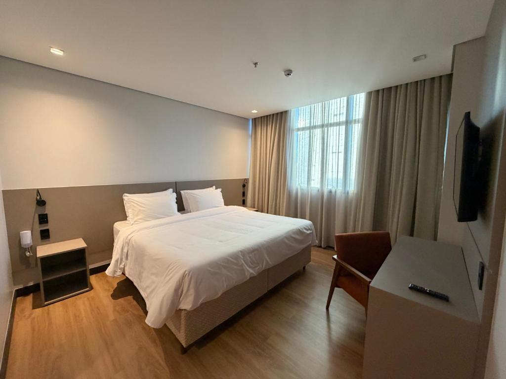 a hotel room with a bed and a television at Hotel Plaza Belmar by HCC in Campo Grande