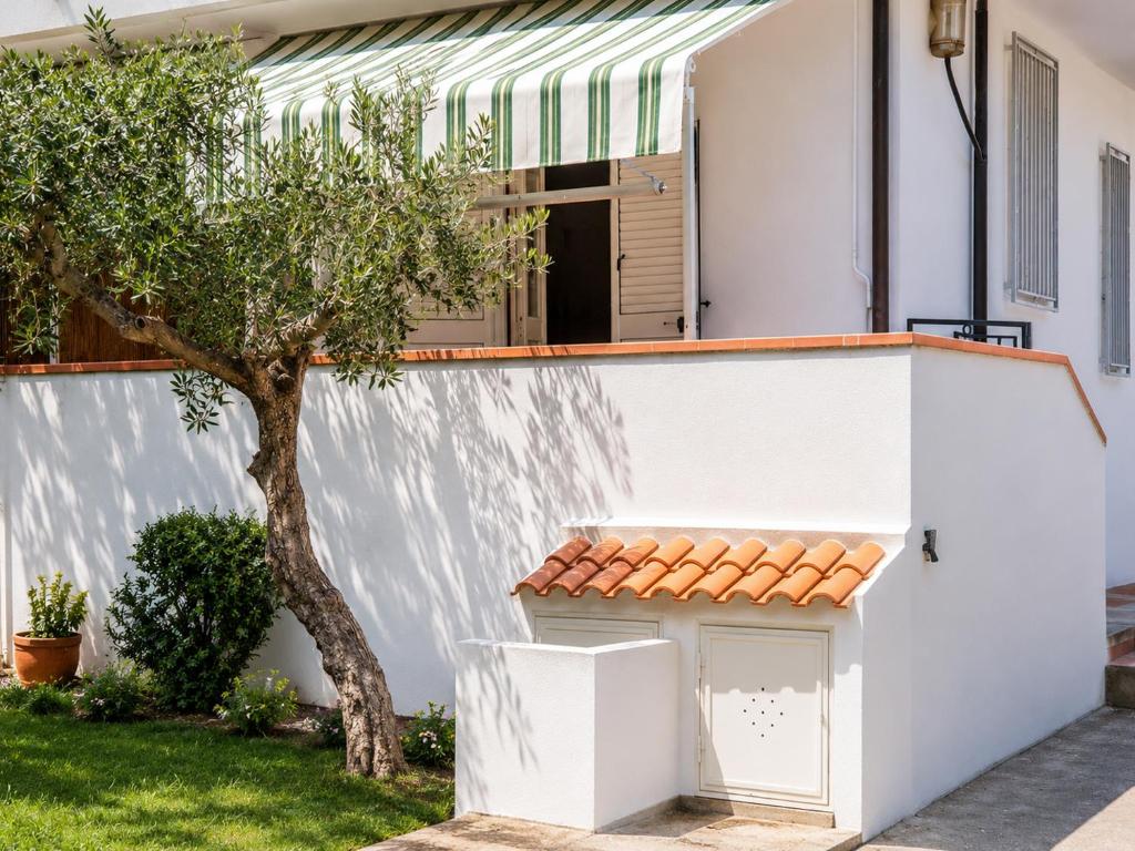 a small white house with a tree in the yard at Appartamenti ABR Porto in Le Castella