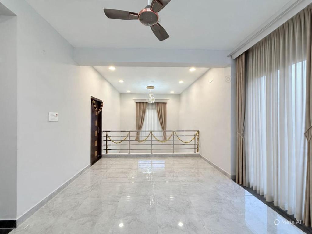 a living room with a ceiling fan and a hallway at Sea shell in Covelong