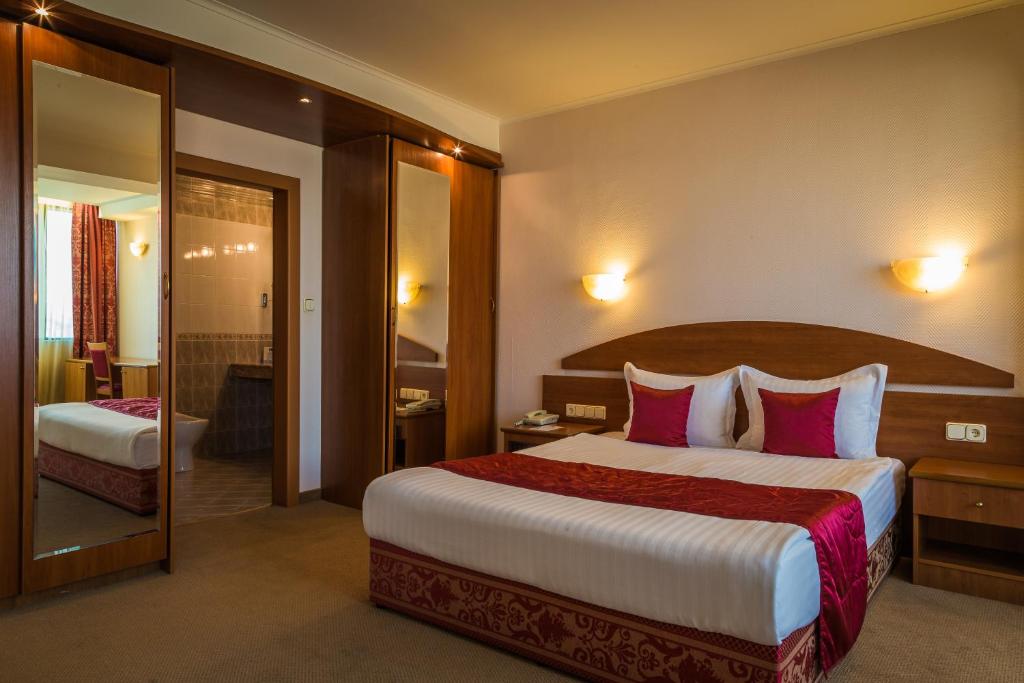 ein Hotelzimmer mit einem großen Bett mit rosa Kissen in der Unterkunft Hotel Sevlievo Plaza in Sewliewo