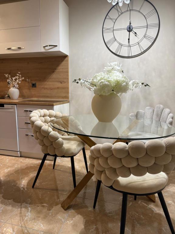 a glass table and two chairs with a vase of flowers at Rosabell in Imotski