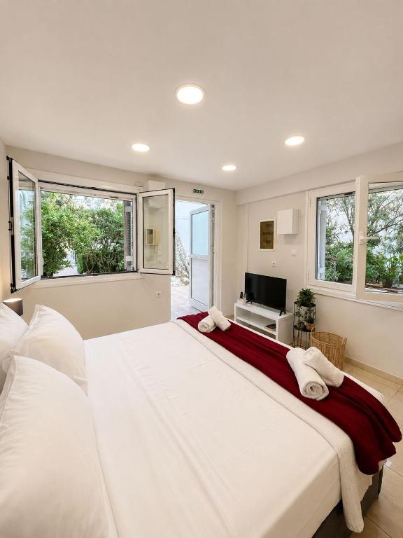 a large white bed in a room with windows at Studio next to the Beach in Vouliagmeni