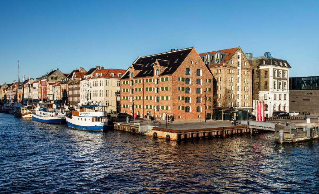 eine Gruppe von Booten, die in einem Fluss mit Gebäuden angedockt sind in der Unterkunft 71 Nyhavn Hotel in Kopenhagen