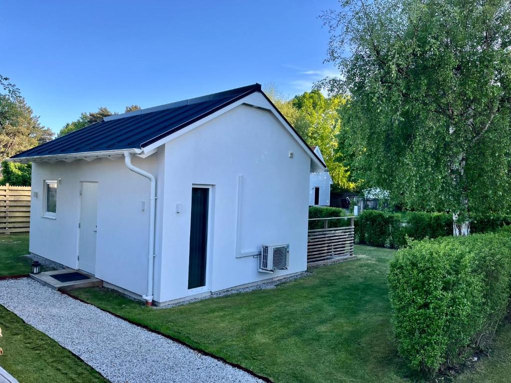 a white shed with a black roof in a yard at Granat's Gästehouse in Höllviken