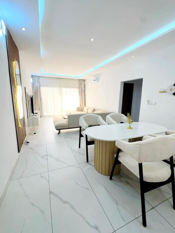 a waiting room with tables and chairs and a couch at Appartement spacieux et confortable in Abidjan