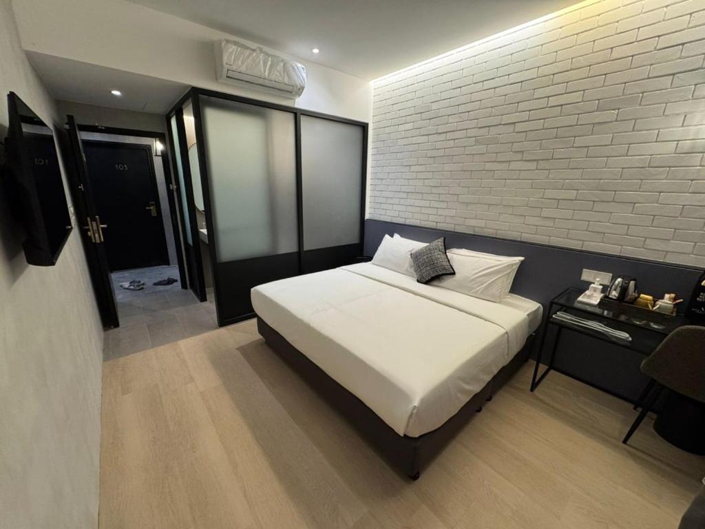a bedroom with a white bed and a brick wall at Atelier Hotel Permas in Johor Bahru