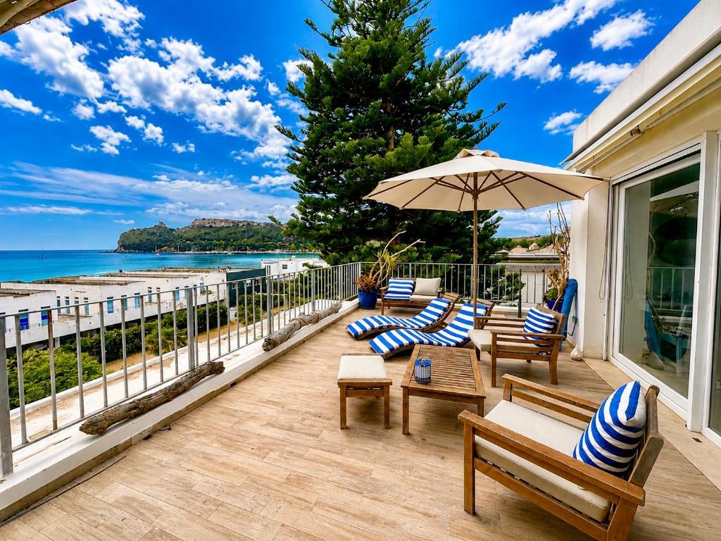 a porch with chairs and an umbrella and the ocean at Il Profumo del Mare GuestHouse in Cagliari
