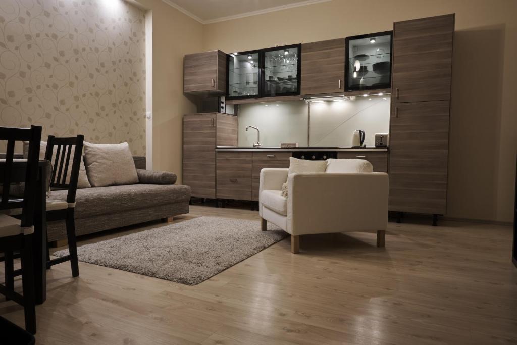 a living room with a couch and a kitchen at K&aacute;rolyi Garden | hostAID in Budapest