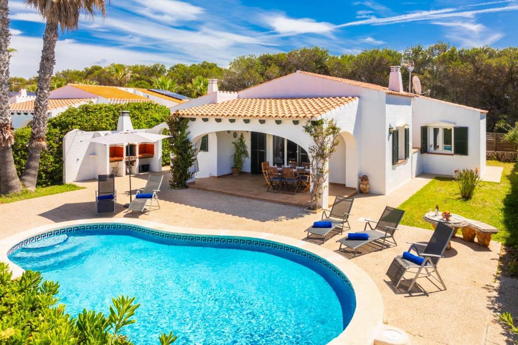 a villa with a swimming pool in front of a house at Villa Miguel Dos in Cala en Bosc